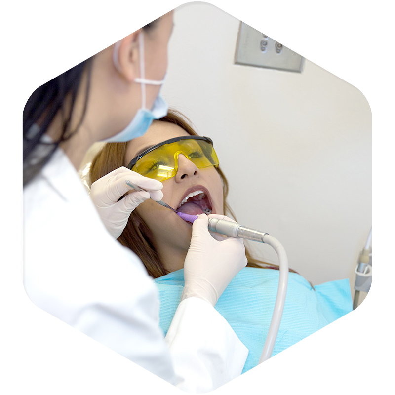 A patient with her mouth open receiving dental treatment from a dentist.